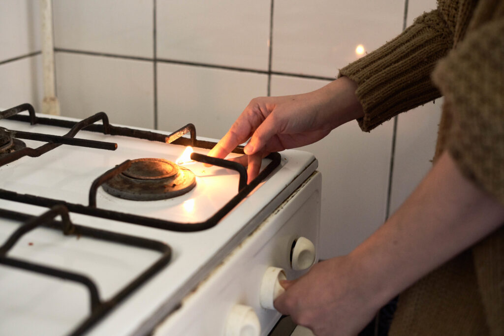 Woman lighting gas stove with match